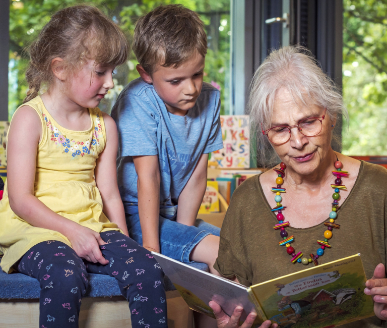 Oma beim vorlesen mit zwei Kindern.